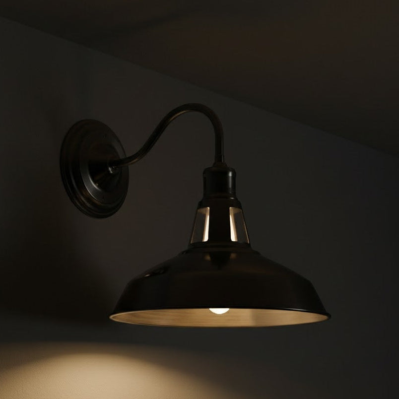 Wall-mounted industrial-style light fixture casting a warm glow on a dark wall.