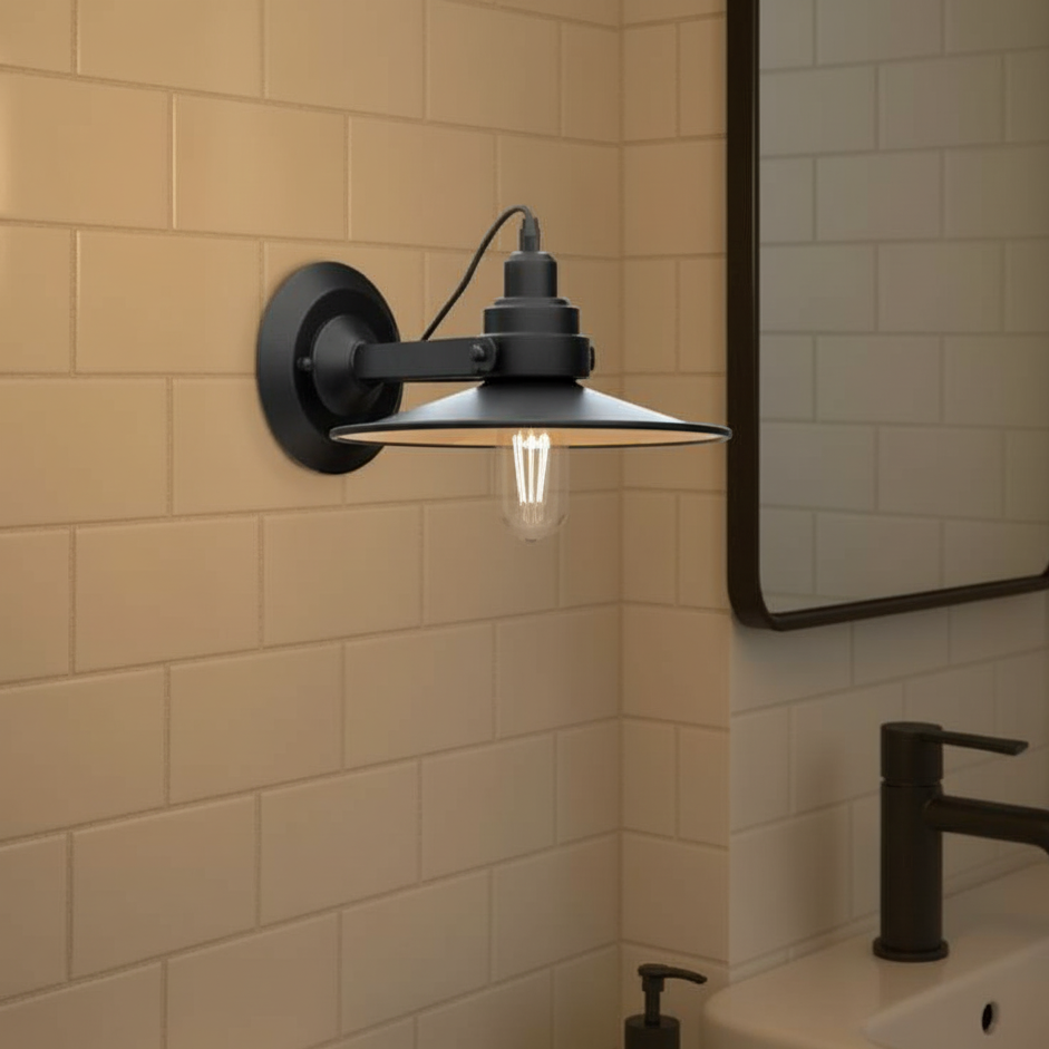 Black wall-mounted light fixture in a bathroom with tiled walls and a mirror.