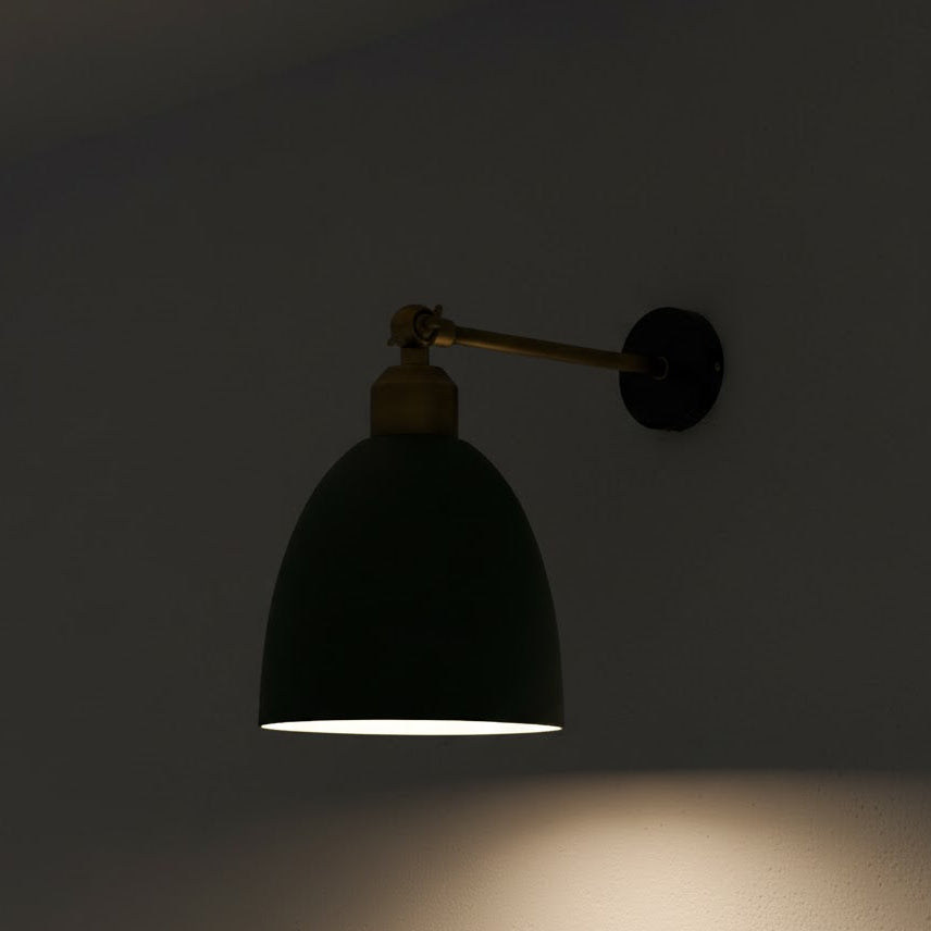 Black wall lamp with gold arm on a dark background