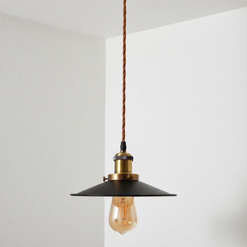 Vintage-style pendant light with a black shade and exposed bulb against a white wall.