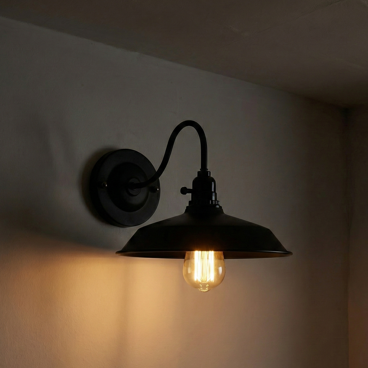 Black wall-mounted lamp with a lit bulb on a dark background