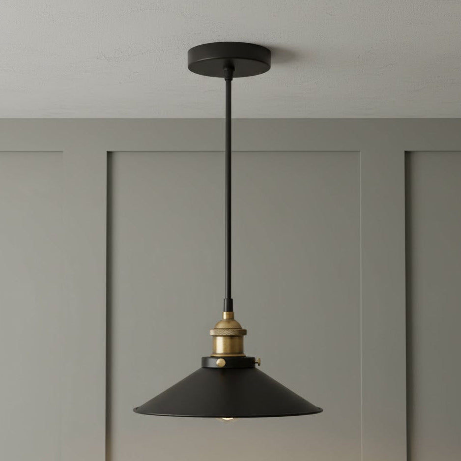 Black pendant light with brass fitting hanging against a gray wall.