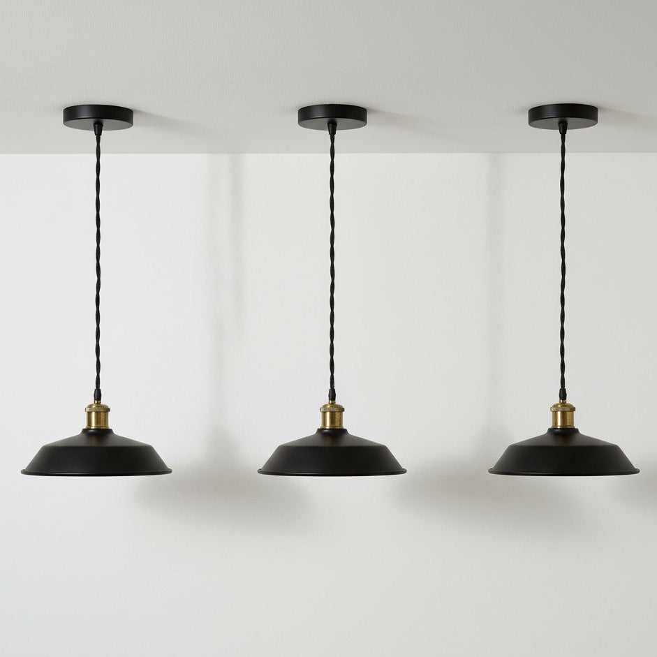 Three black pendant lights with gold accents hanging against a white wall.