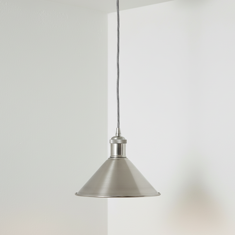 Metal pendant light hanging against a white wall