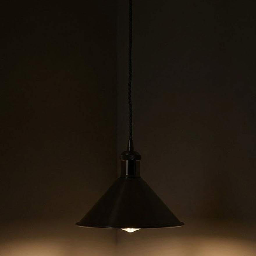 Black pendant light hanging against a dark background