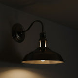 Wall-mounted industrial-style light fixture casting a warm glow on a dark wall.