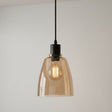 Pendant light with amber glass shade and black fixture on a plain background