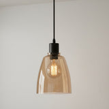 Pendant light with amber glass shade and black fixture on a plain background