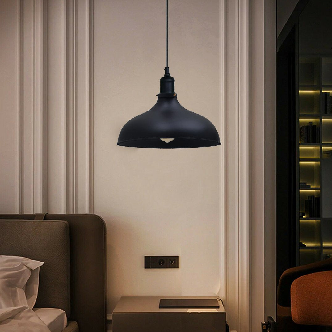 Black pendant light hanging in a modern interior setting with a sofa and wall socket.