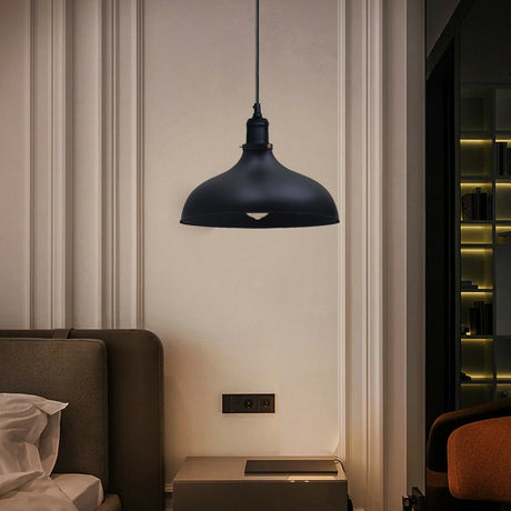 Black pendant light hanging in a modern interior setting with a sofa and wall socket.