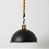 Black pendant light with gold accents and a rope cord on a white background