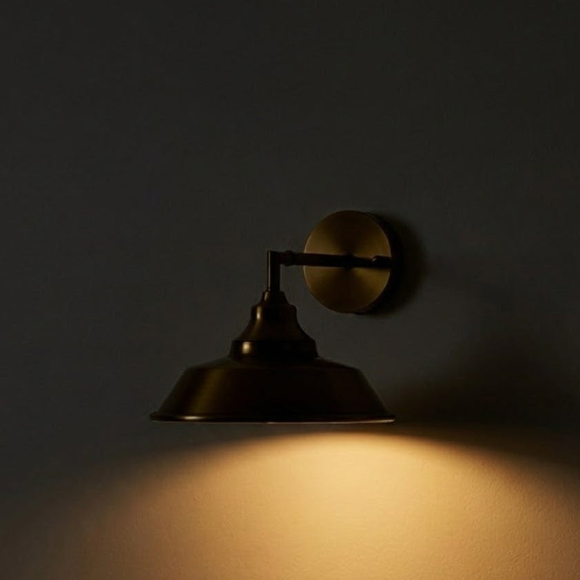 Brass wall sconce casting a warm glow on a dark wall