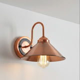 Copper wall sconce with a lit bulb on a white wall