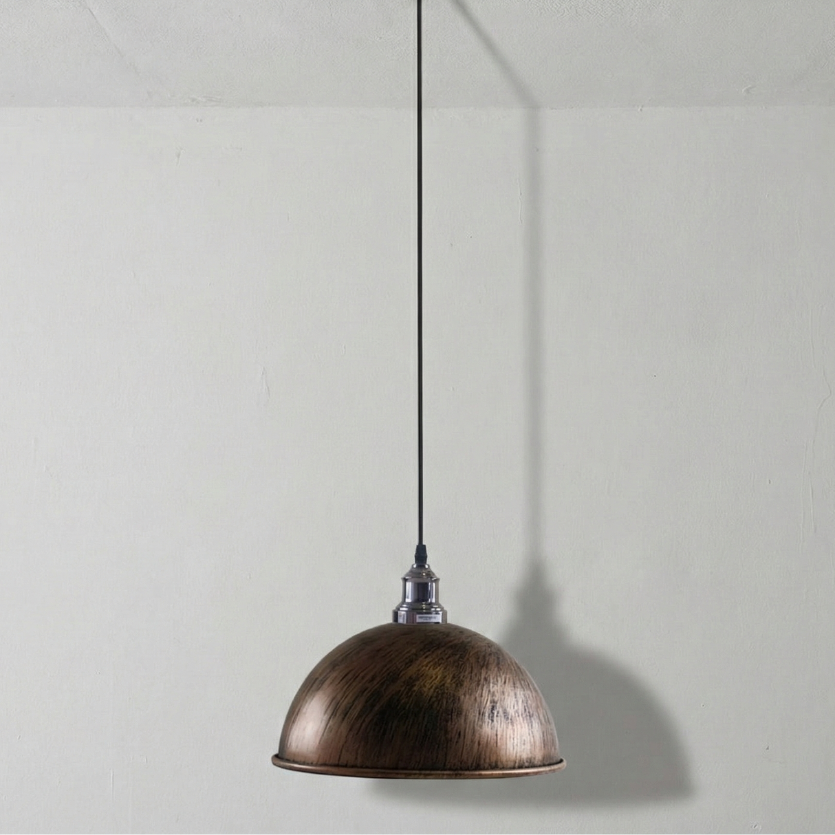 Bronze pendant light hanging against a plain white wall