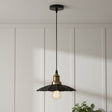 Pendant light with black and gold design hanging against a white paneled wall.