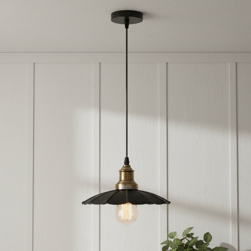 Pendant light with black and gold design hanging against a white paneled wall.