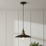 Pendant light with black and gold design hanging against a white paneled wall.