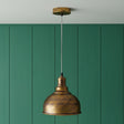 Bronze pendant light against a green paneled wall