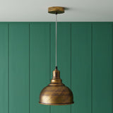 Bronze pendant light against a green paneled wall