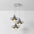 Modern pendant light fixture with three glass shades on a white background