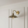 Vintage-style wall sconce with a gold finish on a white paneled wall.