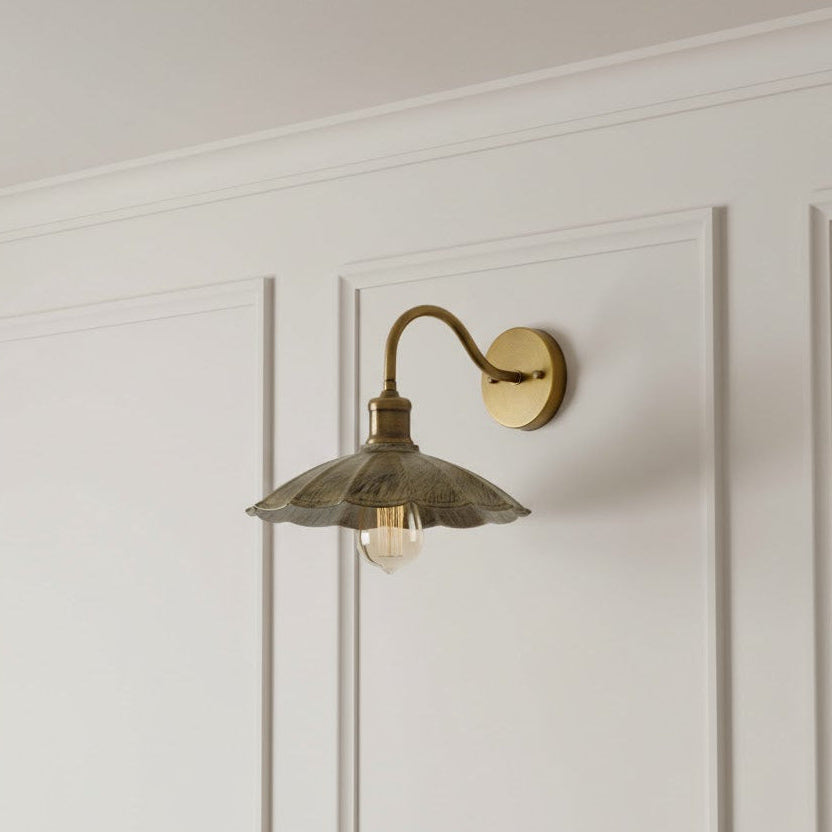 Vintage-style wall sconce with a gold finish on a white paneled wall.