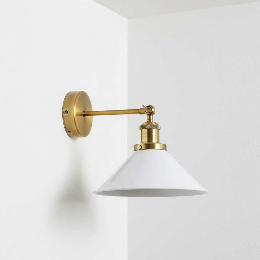 Wall-mounted lamp with brass fixture and white shade on a white background