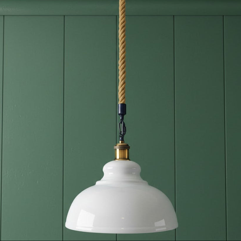 White pendant light with a gold cord against a green paneled wall