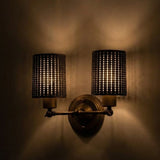Wall-mounted light fixture with two lampshades on a dark wall.