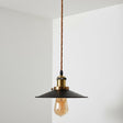 Vintage-style pendant light with a black shade and exposed bulb against a white wall.