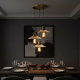 3 pendant light over Dining table set with plates, glasses, and a framed picture on a dark wall.