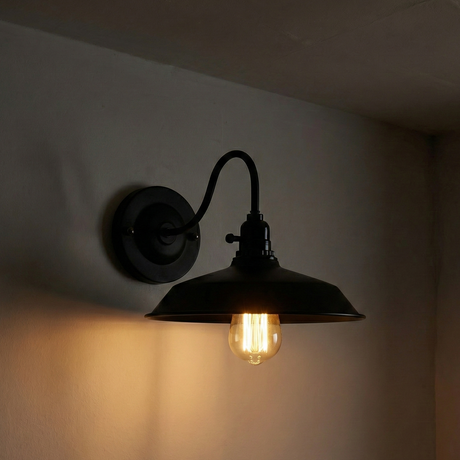 Black wall-mounted lamp with a lit bulb on a dark background