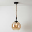 Pendant light with glass shade and rope cord on a white background