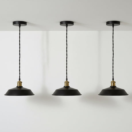 Three black pendant lights with gold accents hanging against a white wall.