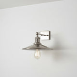 Wall-mounted light fixture with a chrome shade on a white wall