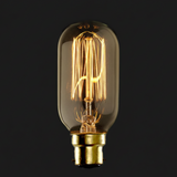 Vintage-style light bulb with clear glass and gold base on a black background