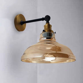 Wall-mounted lamp with gold fixture and clear glass shade on a light gray background