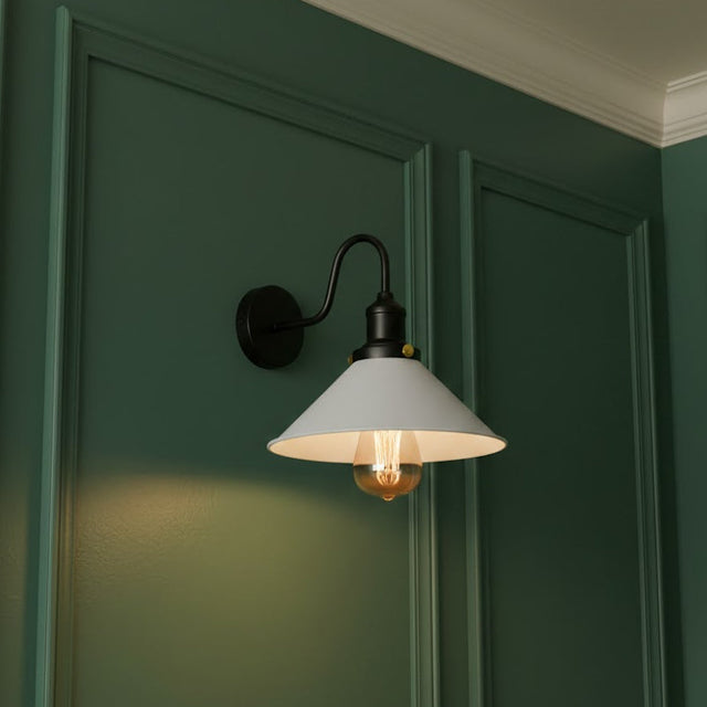 Wall-mounted light fixture with a white shade on a green wall.