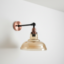Wall-mounted light fixture with copper and glass design on a white wall