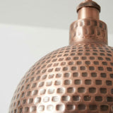Close-up of a textured copper object with a grid pattern on a light gray background