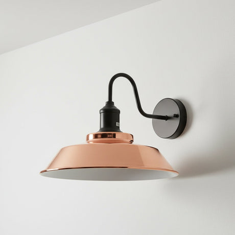 Wall-mounted lamp with copper shade and black arm on a white wall