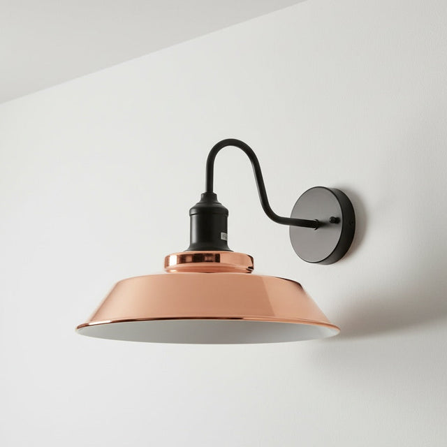 Wall-mounted lamp with copper shade and black arm on a white wall